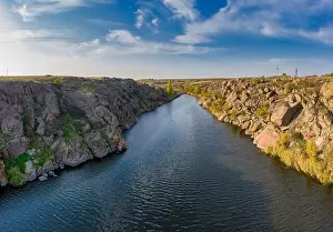 A stream flowing among huge stones covered with small dry plants in the warm evening light in picturesque Ukraine