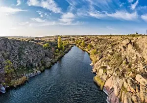 A stream flowing among huge stones covered with small dry plants in the warm evening light in picturesque Ukraine