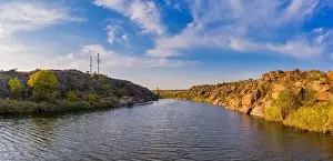 A stream flowing among huge stones covered with small dry plants in the warm evening light in picturesque Ukraine