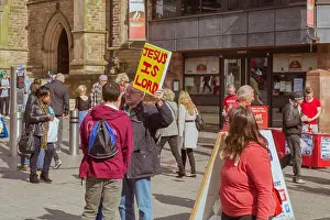 Activism Prints: A street preacher holds up a sign saying Jesus is Lord in a busy city centre shopping area