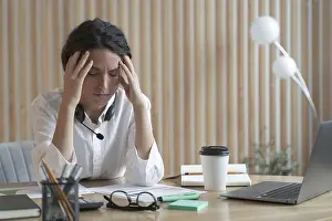 Headache Prints: Stressed woman with headset having headache while working at desk