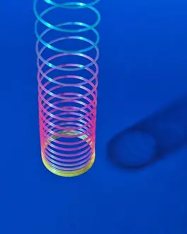 Flexible Prints: Stretching rainbow plastic slinky toy above blue background with shadows, place for text