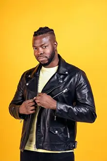 Black Man Prints: Strong black man wearing black leather jacket posing in studio shot against yellow background
