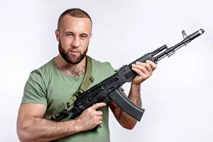 Concentrated Prints: Strong caucasian shooter in casual clothing with sniper rifle looking at camera isolated on white