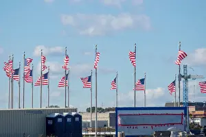 Washington Dc Prints: Strong winds blow flags in different directions at the Washington Monument in Washington DC