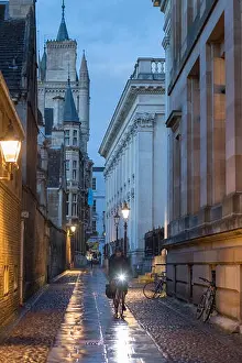 Raindrops Prints: A student cyclist on Senate House Passage at dusk, Cambridge, England, UK