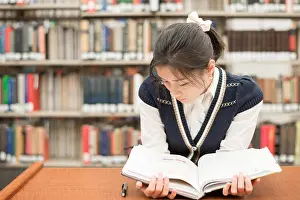 Concentrate Prints: Student reading a textbook in library