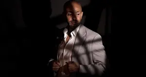 Well Dressed Prints: Studio portrait of a bald man with a beard wearing a gray suit and white shirt in dramatic lighting