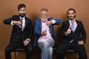 Business Man Prints: Studio shot of three multi ethnic bearded businessmen together against brown background