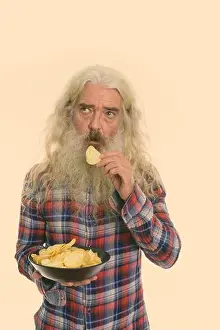 Toned Prints: Studio shot of senior bearded man thinking while eating bowl of potato chips