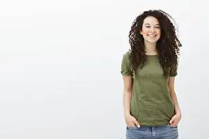 Satisfied Prints: Studio shot of shy cute curly-haired female student in dark-green t-shirt
