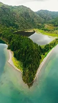 A stunning aerial photograph showcases a majestic lake surrounded by rich green forests in the Azores The serene water