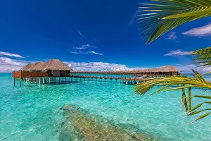 Stunning tourism landscape. Luxurious beach resort, palm trees over calm sea water, beach villas and blue sky. Romantic destination, vacation, holiday