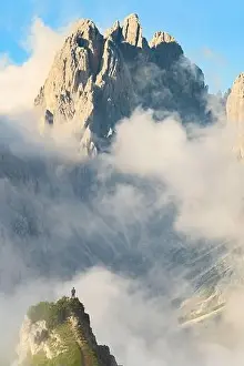 Stunning view of a tourist on the top of a hill enjoying the view of the Cadini di Misurina during a cloudy day