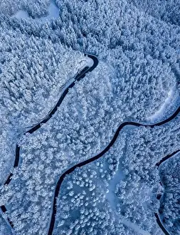Stunning winter scene landscape of snow covered trees and forest as a road cuts through the landscape