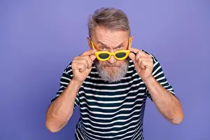 Fashion Model Prints: Stylish elderly man wearing yellow sunglasses and striped shirt posing against a violet background in a cheerful