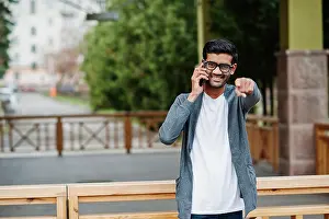 South Asian Prints: Stylish indian man at glasses wear casual posed outdoor and speaking on phone