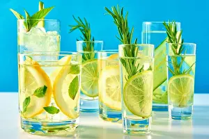 Summer alcoholic cocktail. Refreshment lemon soda drink. Gin and tonic with lime and rosemary on blue background