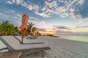 Summer beach landscape. Luxury vacation and holiday concept, summer travel banner. Panoramic landscape of sunset beach, two loungers umbrella, palms