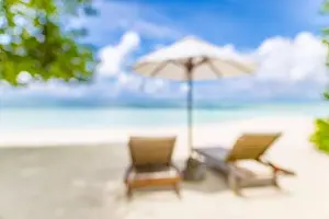 Summer exotic sandy beach with blur palms and sea on background