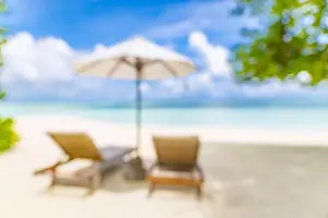 Summer exotic sandy beach with blur palms and sea on background