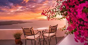 Summer sunset vacation scenic of luxury famous Europe destination. White architecture in Santorini, Greece. Stunning travel scenery with pink flowers