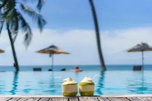 Summer, Travel, Vacation and Holiday concept - Tropical fresh coconut cocktail with pool and beach in ocean, Phuket, Thailand