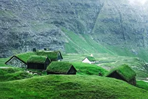 Summer view of traditional turf-top church Saksunar Kirkja in Saksun village. Beauty landscape with grassy houses and high mountains