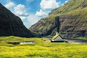 Summer view of traditional turf-top church Saksunar Kirkja in Saksun village. Beauty landscape with Pollurin Laguna and high mountains