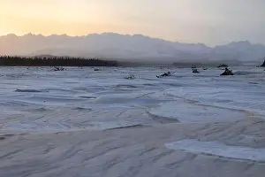 Delta Junction Prints: Sun rising over Alaska range behind a frozen river covered in snow along the Alaska Highway on the winter solstice near