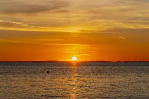 The sun about to set over the Welsh coast with a reddish orangey glow along the horizon