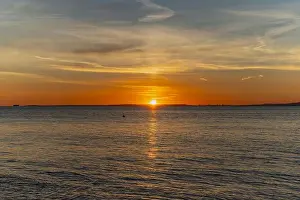 The sun about to set over the Welsh coast with a reddish orangey glow along the horizon