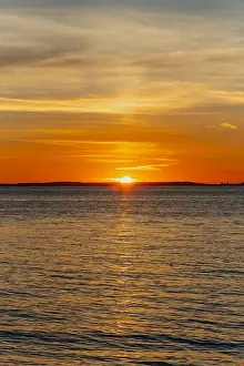 The sun about to set over the Welsh coast with a reddish orangey glow along the horizon