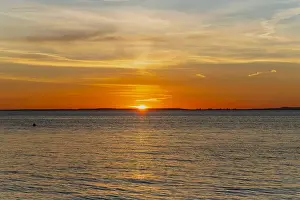 The sun about to set over the Welsh coast with a reddish orangey glow along the horizon