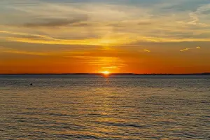 Welsh Coast Prints: The sun about to set over the Welsh coast with a reddish orangey glow along the horizon
