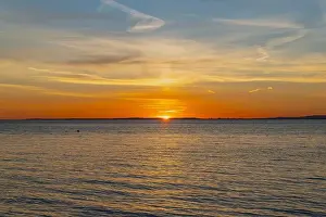 Welsh Coast Prints: The sun about to set over the Welsh coast with a reddish orangey glow along the horizon