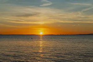 The sun setting over the Welsh coast with a streak of Sunlight going across the sea