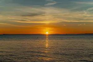 The sun setting over the Welsh coast with a streak of Sunlight going across the sea