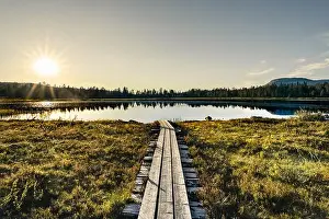 Sunbeams shine over the serene forest lake in Idre Dalarna