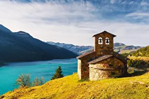 Sunny picturesque view of stone chapel on Roselend lake (Lac de Roselend) in France Alps (Auvergne-Rhone-Alpes). Landscape photography