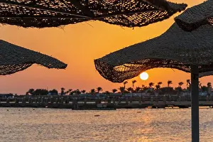 Disorder Prints: Sunrise on the beach with parasol overlooking the Red Sea in Hurghada, Egypt