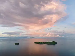 Sunrise illuminates clouds that drift over the calm waters of the Solomon Islands. This scenic region is known for its high marine biodiversity