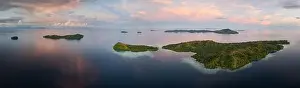 Sunrise illuminates clouds that drift over the calm waters of the Solomon Islands. This scenic region is known for its high marine biodiversity