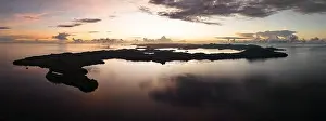 Sunrise illuminates clouds that drift over the calm waters of the Solomon Islands. This scenic region is known for its high marine biodiversity