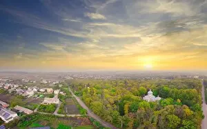 Sunrise over the park located in the village. Fog over the trees and the church in the park
