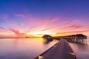 Images Dated 12th January 2017: Sunset on Maldives island, luxury water villas resort and wooden pier. Beautiful sky and clouds