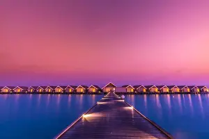 Sunset on Maldives island, luxury water villas resort and wooden pier. Beautiful sky and clouds and beach background for summer vacation holiday