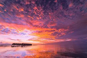 Sunset on Maldives island, luxury water villas resort and wooden pier. Beautiful sky and clouds and beach background for summer vacation holiday
