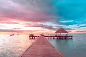 Sunset on Maldives island, luxury water villas resort and wooden pier. Beautiful sky and clouds and beach background for summer vacation holiday