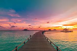 Sunset on Maldives island, luxury water villas resort and wooden pier. Beautiful sky and clouds and beach background for summer vacation holiday